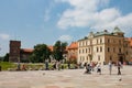 a group of people walking in a courtyard near buildings with pigeons on a patio