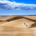 Group of people walking over sand dunes under a cloudy sky Royalty Free Stock Photo