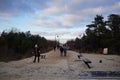 Group of people walking on a sandy path leading to the beach on a cloudy day in Swinoujscie, Poland