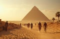 A group of people walking on a sandy road in front of the pyramids Royalty Free Stock Photo