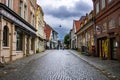 A group of people walks a vacant cobblestone street in the city center of Bergen, Norway after a rainstorm