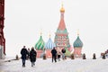 A group of people in warm clothes crosses Red Square against the background of St. Basil`s Cathedral. Selective focus