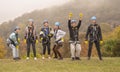 Group of people in zipline equipment pose merrily against the backdrop of the autumn forest