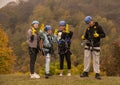 Group of people in zipline equipment pose merrily against the backdrop of the autumn forest