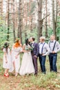 The group photo of the groom and his best men, the bride with the bridemaids at the background of the pine green forest