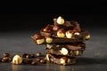 Group of pieces of dark chocolate with whole hazelnuts, closeup on a dark background. Black chocolate with hazelnuts nuts close-up