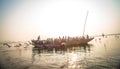 Pilgrims approaching the East bank of the sacred Ganges river by boat at sunrise in Varanasi, Uttar Pradesh, India.