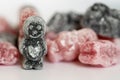 A group of pink and black jelly sweets with a dark sweet figure with a heart emblem on its front standing