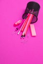 Group of pink color stationery products are scattered from pencil bin from top to bottom on pink background isolated