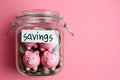 Group of pink piggy banks in a glass jar on pink. Personal savings and financial investment, money storage, money boxes. Finance