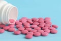Group of pink round pills and white bottle on a blue background Royalty Free Stock Photo