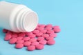 Group of pink round pills and white bottle on a blue background Royalty Free Stock Photo