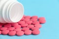 Group of pink round pills and white bottle on a blue background Royalty Free Stock Photo