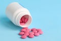 Group of pink round pills and white bottle on a blue background Royalty Free Stock Photo