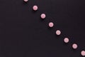 Group pink tablets. Black background. Line, way course concept.