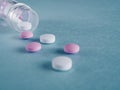 Group of pink and white round medicine pills and bottle on a blue background. Selective focus. Shallow depth of field. Theme of Royalty Free Stock Photo