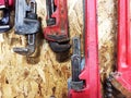 Group of pipe wrenches hanging on wooden wall.