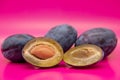 Group of plums with plum leaves isolated on a pink background Royalty Free Stock Photo