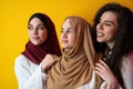 Group portrait of beautiful Muslim women two of them in a fashionable dress with hijab isolated on a yellow background Royalty Free Stock Photo