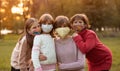 Group portrait of children in protective medical masks walking on street on sunset Royalty Free Stock Photo