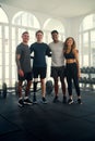 Group portrait of happy multiracial young adults in sports clothing looking at camera at the gym