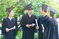 Group of Portrait happy students in graduation gowns holding diplomas on university campus Royalty Free Stock Photo