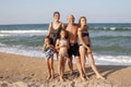 Group portrait of a healthy family of 5 people, mom, dad and three daughters on a sunny beach are standing on the sand
