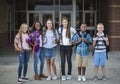 Group portrait of pre-adolescent school kids smiling in front of the school building