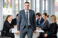 Group portrait of six business people team sitting and talking in conference together in an office and while the man boss stand Royalty Free Stock Photo