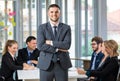 Group portrait of six business people team sitting and talking in conference together in an office and while the man boss stand Royalty Free Stock Photo