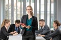 Group portrait of six business people team sitting and talking in conference together in an office and while the woman boss stand Royalty Free Stock Photo