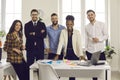 Team of happy young diverse business people standing in modern office and smiling Royalty Free Stock Photo