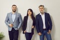 Group portrait of three business people standing together by white wall at work in office Royalty Free Stock Photo