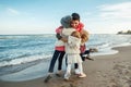 Group portrait of white Caucasian family, mother with three children kids hugging smiling laughing on ocean sea beach on sunset Royalty Free Stock Photo