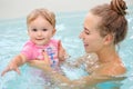 Group portrait of white Caucasian mother and baby daughter playing in water diving in swimming pool inside, training to swim, heal Royalty Free Stock Photo