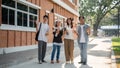 Group of positive Asian students are in their campus, smiling and waving their hands to the camera Royalty Free Stock Photo