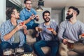 Positive male friends drinking beer and eating pizza at home