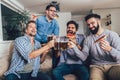 Positive male friends drinking beer and eating pizza at home