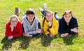 Group of positive teenagers lying on green grass