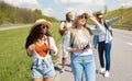 Group of positive young friends walking along highway, making photos, having fun together outdoors Royalty Free Stock Photo