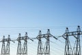 Group of posts with wires of high voltage on background of blue sky. Background image of pillars and wires in sky with copy space Royalty Free Stock Photo