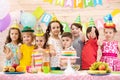 Group of children having fun celebrating birthday party. Kids showing thumbs up sign