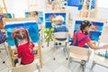 A group of preschool students and young teacher in drawing class paint in gouache. mixed race schoolgirl afroamerican