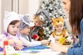 Group of preschoolers weared funny clothes on lesson in classroom. Kids with teacher make hands crafts in kindergarten Royalty Free Stock Photo