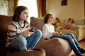 A group of preteen kids playing video games at home. Children sitting on the couch together holding gaming controllers Royalty Free Stock Photo