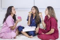 Group of pretty teenage girls eating donuts in bed
