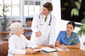 Group of professional doctors sitting at table and discussing diagnosis and treatment of patients during medical council