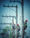 Group of professional electrical linemen performing maintenance and installation on high-voltage power lines Royalty Free Stock Photo