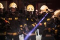 Group of professional firefighters. Firemen wearing uniforms, protective helmets and oxygen masks. Smoke in the background