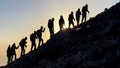 Group of professional mountaineers hiking towards peak mountains at sunrise